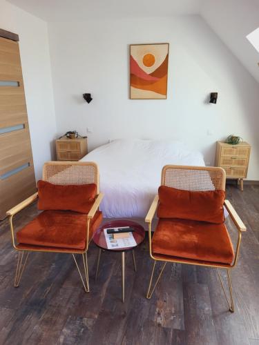 two chairs and a table in a room with a bed at Aparthotel Des 2 Caps in Ambleteuse