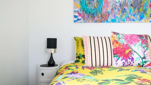 a bedroom with a bed with colorful pillows and a painting at LACROIX - DAYLESFORD in Daylesford
