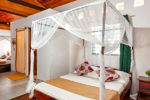 a bedroom with a canopy bed with white curtains at A casa di Giorgia lodge Nosy be Andilana in Nosy Be
