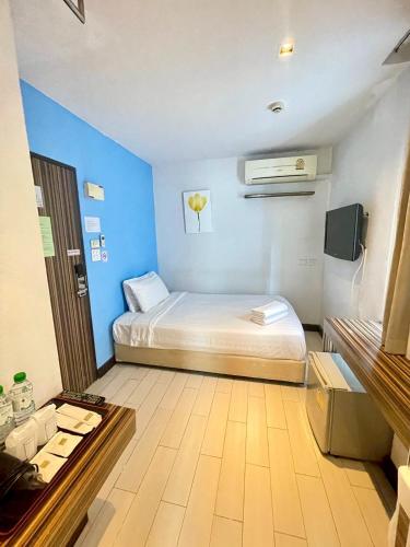 a small room with a bed and a blue wall at Nantra Ekkamai Hotel in Bangkok