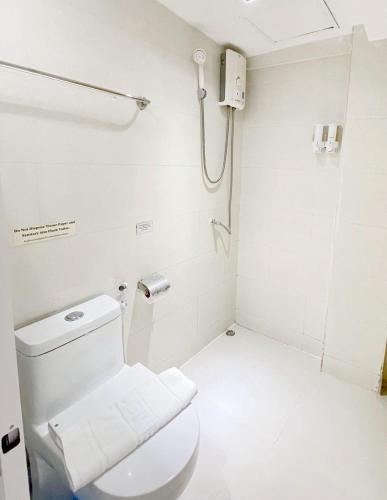 a white bathroom with a toilet and a shower at Nantra Ekkamai Hotel in Bangkok