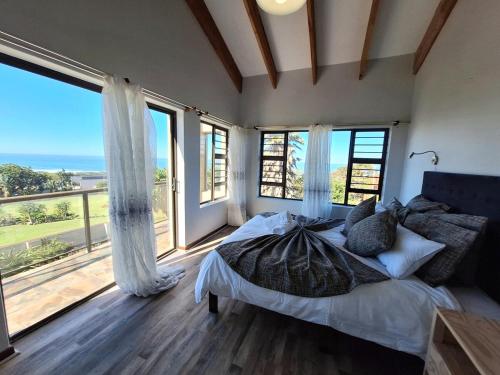 a bedroom with a large bed and large windows at Barefoot Bliss Holiday Home in Port Alfred