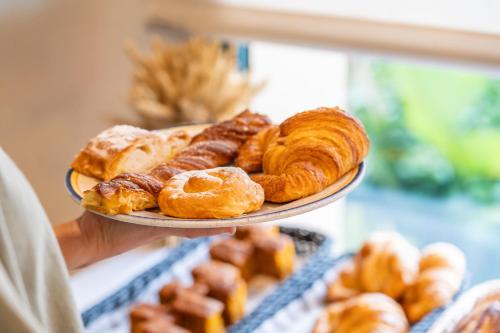 una persona sosteniendo un plato de pasteles y croissants en La Quinta Menorca by PortBlue Boutique - Adults Only, en Cala'n Bosch