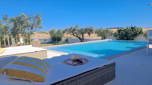 a swimming pool with a hat on a bed next to it at LALOU Casinhas B&B in Mértola
