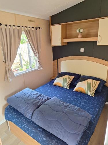 a bedroom with a bed with blue sheets and a window at KD 814 - Vakantiepark Kijkduin in Kraaijenstein