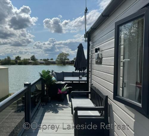 a deck with chairs and a couch on the side of a house at Lakeside Retreat with hot tub and fishing peg on Osprey Rise at Tattershall Lakes Country Park in Tattershall