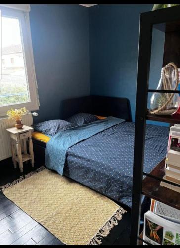 ein Schlafzimmer mit einem Bett mit einer blauen Wand in der Unterkunft Chambre double proche du circuit in Le Mans