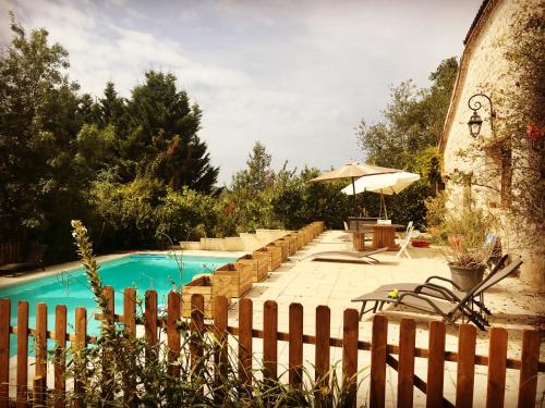 - une piscine avec une clôture et un parasol dans l'établissement Gîte de charme à la campagne, à Lusignan-Petit