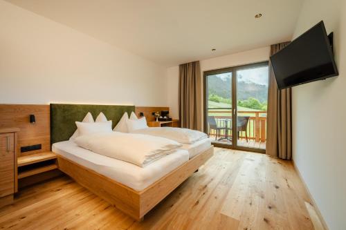 a bedroom with a large bed with a flat screen tv at Ferienhof Obergasser und Bergblick in Weissensee