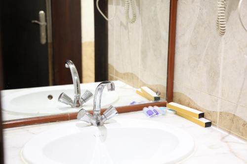a bathroom sink with two faucets in front of a mirror at فندق الفالح للوحدات الفندقيه in Al Baha