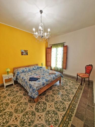 a bedroom with a bed and a chair and a chandelier at A Casa da Vita in Chiaramonte Gulfi