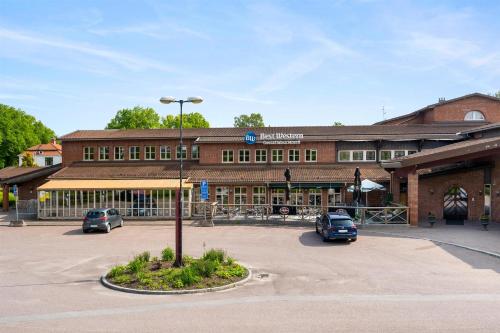 ボルレンゲにあるBest Western Gustaf Wasa Hotelの大きなレンガ造りの建物と駐車場に駐車された車