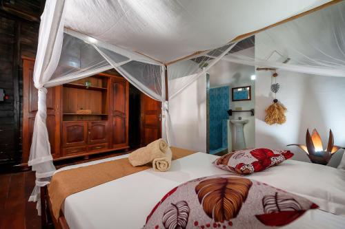 a bedroom with two beds and a canopy bed at A casa di Giorgia lodge Nosy be Andilana in Nosy Be