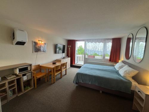Un dormitorio con una cama, una mesa y un escritorio. en Hainz Panorama Deluxe Fernblick mit Sauna und Pool, en Sankt Englmar