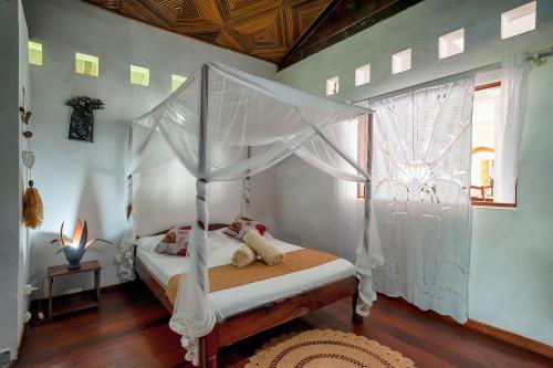 a bedroom with a canopy bed and a window at A casa di Giorgia lodge Nosy be Andilana in Nosy Be