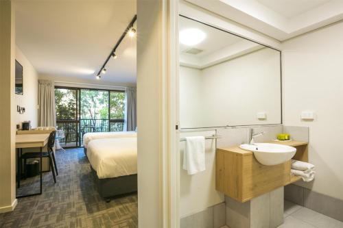a bathroom with a bed and a sink and a mirror at Nightcap at Kawana Waters Hotel in Kawana Waters