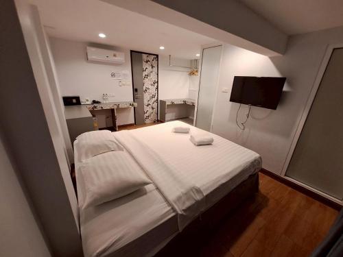 a bedroom with a large bed and a television at Nantra Ploenchit hotel in Bangkok