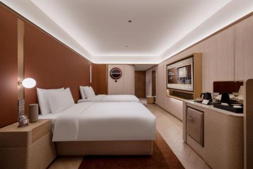 a bedroom with a large white bed and a kitchen at Orange Crystal Hotel MixC Shantou East Coast in Shantou