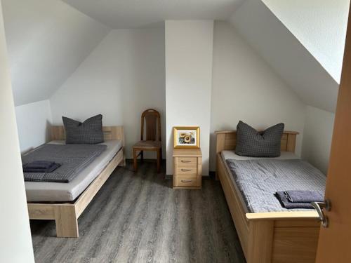 a bedroom with two beds and a chair in it at Ferienwohnung Christa in Hähnichen