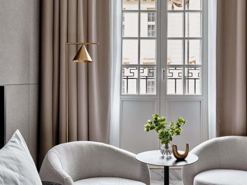 a living room with two chairs and a table and a window at Mövenpick Grand Hotel Wroclaw in Wrocław