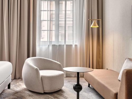 a living room with a chair and a couch at Mövenpick Grand Hotel Wroclaw in Wrocław