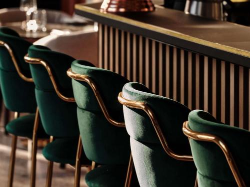 a row of green chairs in front of a counter at Mövenpick Grand Hotel Wroclaw in Wrocław
