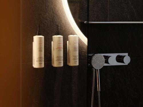 three white shampoo bottles on a wall in a bathroom at Swissôtel Damian Jasna in Demanovska Dolina