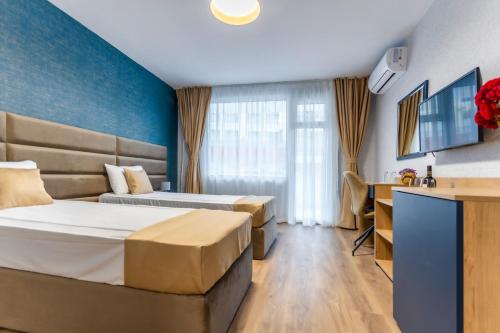 a hotel room with two beds and a desk at Hotel Laguna SPA in Sveti Vlas