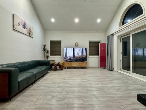 a living room with a green couch and a large window at Daeboodo Prince Pension in Ansan