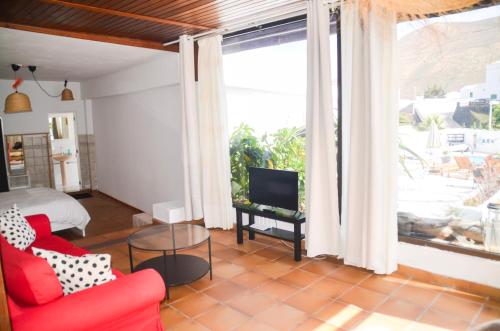 a living room with a red couch and a tv at HOTELITO RURAL GA7COLORES only adult in Montaña Blanca