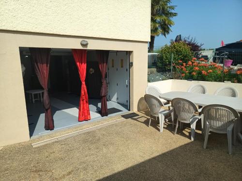 a patio with a table and chairs and red curtains at Le Studio in Saint-Martin-des-Tilleuls