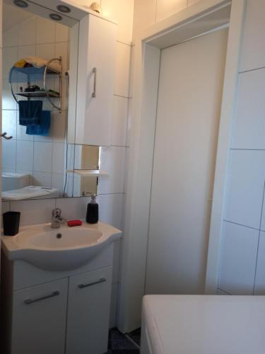 a white bathroom with a sink and a mirror at Apartman Renata in Pula
