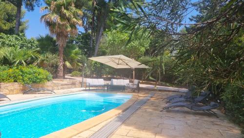 une piscine avec une table et un parasol dans l'établissement villa provençale avec piscine,proche mer, à La Ciotat