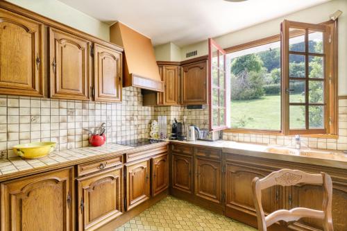 une cuisine avec des armoires en bois et une fenêtre dans l'établissement L'Asylum - 1000 m2 de jardin, à La Rivière-Saint-Sauveur