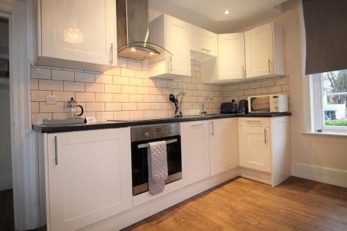 a kitchen with white cabinets and a stove top oven at The Fraya Suite at Sterling house Short Stays in Basingstoke
