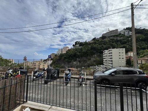 une voiture et des motos garées à côté d'une clôture dans l'établissement Joli appartement 2 pièces à 5 min de Monaco, à Beausoleil