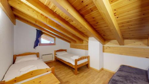 due letti in una stanza con soffitti in legno di Pracondu 2 501 - OUTDOOR & FUN apartment 14 pers a Nendaz