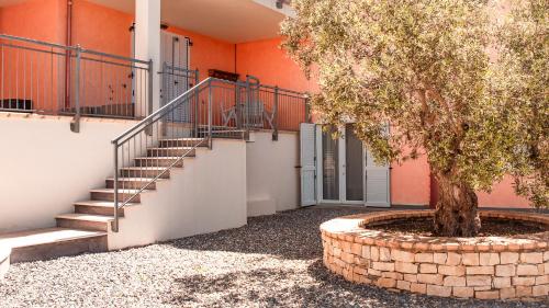 a staircase with a tree in front of a building at Teuladamar by Rentbeat in SantʼAnna Arresi