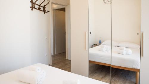 a white bedroom with a mirror and a bed at Teuladamar by Rentbeat in SantʼAnna Arresi