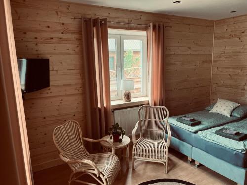 a bedroom with a bed and two chairs and a window at Nad stawami - apartament in Białowieża