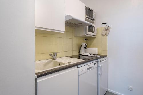 une petite cuisine avec des armoires blanches et un évier dans l'établissement Le Chitelet 506 - Au pied des pistes, à La Bresse