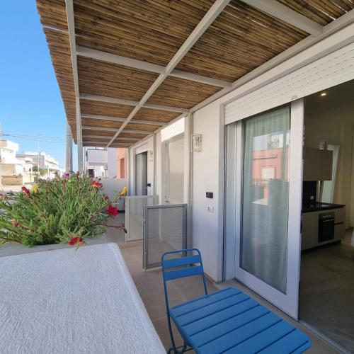 a patio with a table and blue chairs on a balcony at Azzurro Mare Aparthotel in Torre Mozza