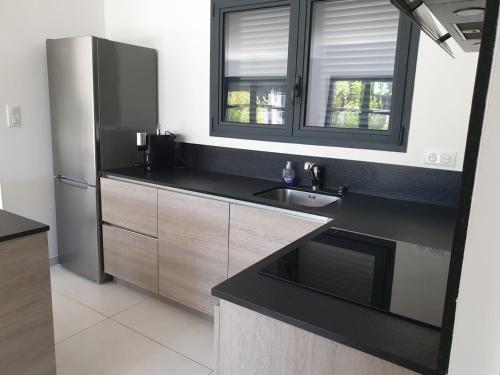 une cuisine avec un évier et un réfrigérateur dans l'établissement Maison moderne 300m de la plage rochelongue, au Cap d'Agde