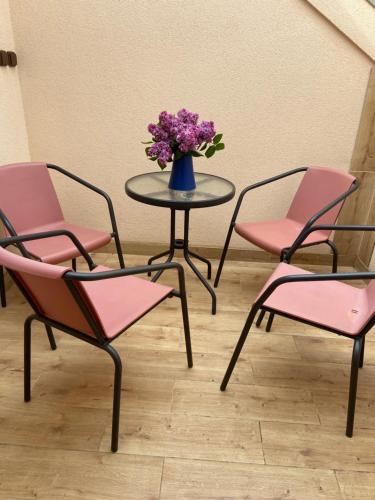 a table with pink chairs and a vase with purple flowers at Apartmán KUGA in Mikulov