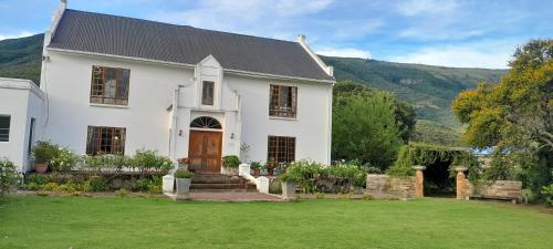 a white house with a green lawn in front at Bell Guesthouse in Somerset East
