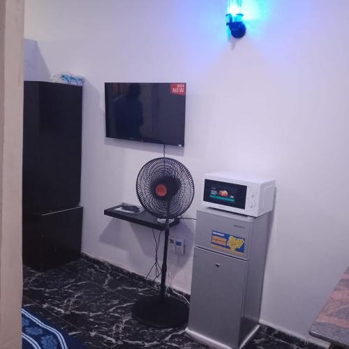 a room with a fan and a television on a wall at Peace Home in Lekki