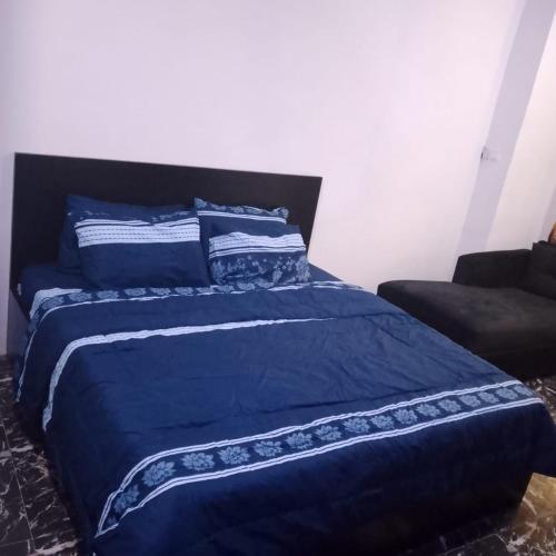 a blue bed with a blue comforter and a couch at Peace Home in Lekki