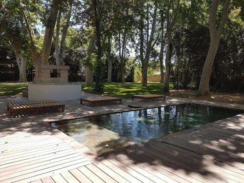 une piscine dans un parc avec des bancs et des arbres dans l'établissement Exceptional building on 1 ha of private land, à Marsillargues