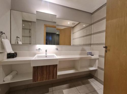 ein Badezimmer mit Waschbecken und großem Spiegel in der Unterkunft The Pearls Umhlanga in Durban