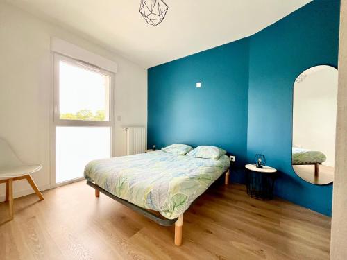 une chambre avec des murs bleus et un lit et une fenêtre dans l'établissement Superbe appartement extérieur, 2 chambres, parking, à La Rochelle